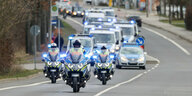 Polizeimotorräder vor Polizeiautos auf einer Straße