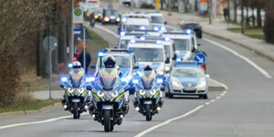 Polizeimotorräder vor Polizeiautos auf einer Straße