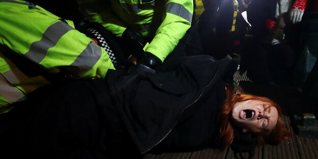 Eine Frau wird von Polizisten zu Boden gedrückt , sie schreit