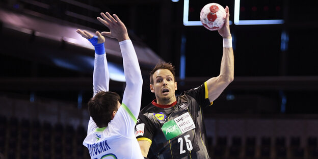 Ein Handballer wirft, ein anderen streckt die Händer zur Verteidigung nach oben.