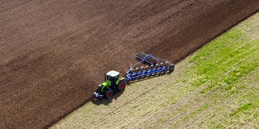 Ein Landwirt pflügt ein abgeerntetes Feld und bereitet es für die Neubestellung vor (Luftaufnahme mit einer Drohne)