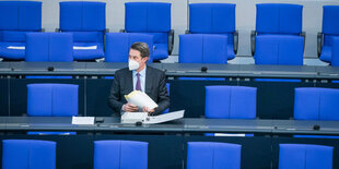 Verkehrsminister Andreas Scheuer sitzt alleine auf einem blauen Stuhl im Bundestag