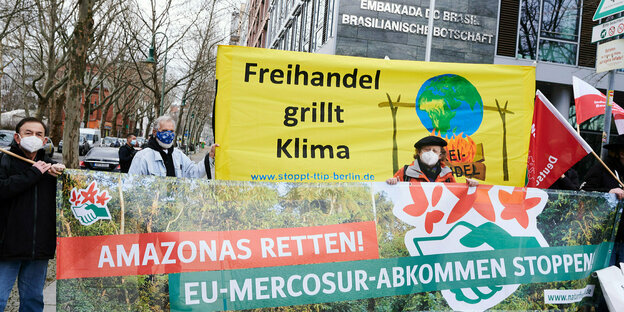 Demonstranten mit Transparenten mit den Aufschriften "Freihandel grillt Klima" (oben) und "Amazonas retten! EU-Mercosur-Abkommen stoppen» stehen vor der Brasilianischen Botschaft