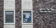 Weiße Kameras an einem Backsteingebäude mit vergitterten Fenstern