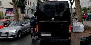 Fahrradfahrer quetscht sich zwischen zwei Autos durch