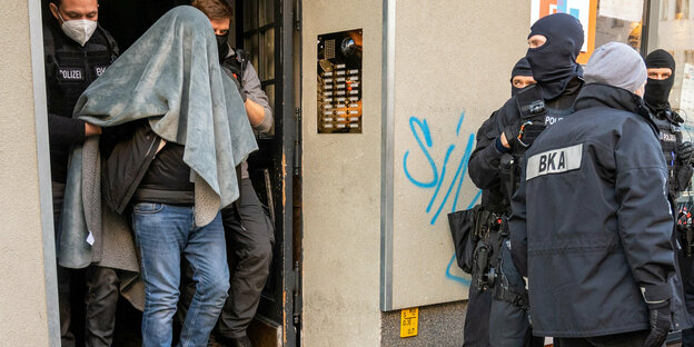 Februar 2021: Ein Mann wird bei einer Großrazzia gegen Clankriminalität in Berlin mit einer Decke über dem Kopf abgeführt