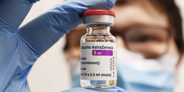 Eine Frau mit Brille hält Impfampulle mit dem Covid19 Impfstoff AstraZeneca