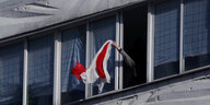 Eine Person winkt mit einer rot-weißem Flagge aus einem Fenster in Minsk