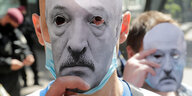 Zwei Männer halten sich schwarz weiß Masken des belarussischen Präsidenten Alexander Lukaschenko vors Gesicht