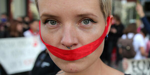 Bei einem Protest belarussischer Studenten hat eine Frau ihren Mund mit einem roten Band verschlossen