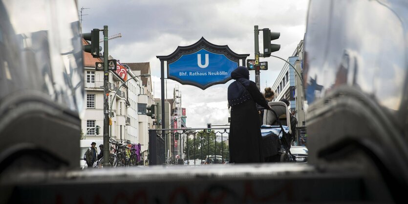 Frau mit Kindewagen aus dem Ausgang der U-Bahn Rathaus Neukoelln in Berlin