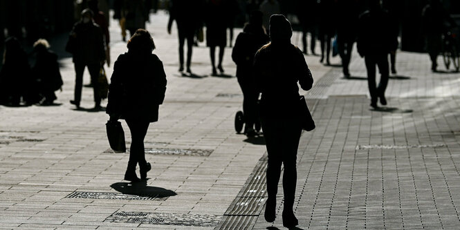 Passanten in einer Einkaufsstrasse im Gegenlicht