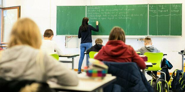 Schüler in einem Klassenzimmer, vorne an der Tafel eine Lehrerin