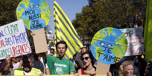 junge Menschen halten Plakate hoch, die die Erde und den Spruch "Je t'aime" zeigen"