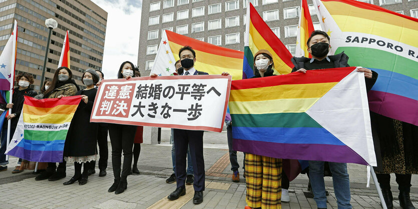 Menschen demonstrieren mit Regenbogenflaggen