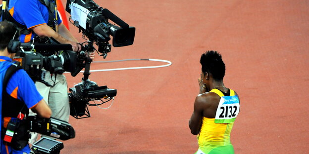 Zwei Kameramänner nehmen eine Olympia-Sportlerin auf