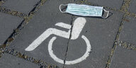 Rollstuhl-Symbol auf Parkplatz - Mundschutz verdeckt Kopf des Rollstuhlfahrer-Symbols