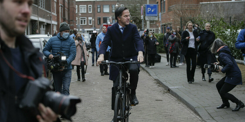 Ein Mann fährt auf einem Fahrrad, um ihn herum stehen viele Menschen