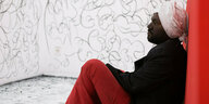 Der Künstler Sajan Mani sitzt zwischen den Wänden, die er mit Kohle bezeichnet hat