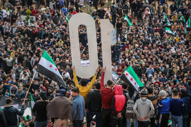 Menschen schwenken Fahnen der syrischen Opposition.