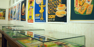 Plakate an einer Wand und persönliche Gegenstände in einer Vitrine ausgestellt