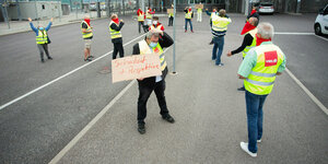 Gewerkschafter in Verdi-Warnwesten vor einer Pforte