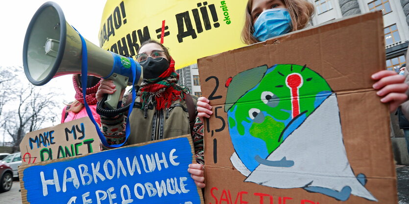 Menschen mit Megafon und Schildern bei einer Demonstration.