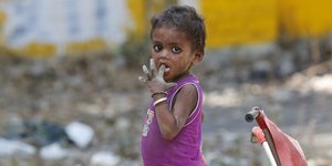 Ein Kind auf der Straße steckt seinen Finger in den Mund