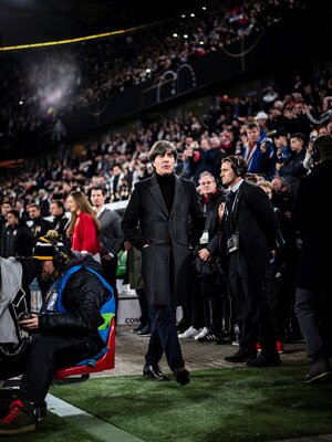 Jogi Löw in schwarzem Mantel läuft im Stadion zwischen den Zuschauern hindurch Jogi Löw in schwarzem Mantel läuft im Stadion zwischen den Zuschauern hindurch