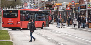 Ein Bus fährt an einer Haltebucht mit wartenden Menschen ein