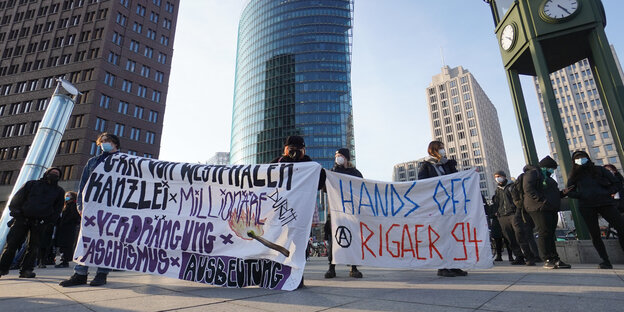 Demonstrant:innen stehen mit Transparenten am Potsdamer Platz in Berlin. "Hands off Rigaer 94" steht auf einem davon.