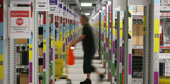 Ein Mitarbeiter transportiert 2017 beim Amazon Logistikzentrum in Rheinberg (Nordrhein-Westfalen) Waren für den Versand.