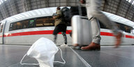 Zwei Reisende auf dem Bahnsteig neben einem ICE - auf dem Boden liegt eine Gesichtsmaske