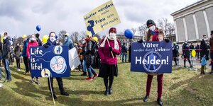 Drei Frauen halten auf einer Demonstration in München Plakate hoch
