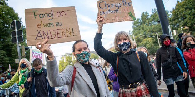 Zwei Aktivistinnen halten bei der Demonstration der Klimaschutzbewegung Fridays for Future Plakate mit der Aufschrift "Fangt an etwas zu ändern!" und "Change the system, not the climate".