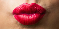 Lippen, die rot angemalt worden sind und einen Kussmund formen.
