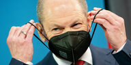Bundesfinanzminister Olaf Scholz setzt eine schwarze FFP2-Maske auf