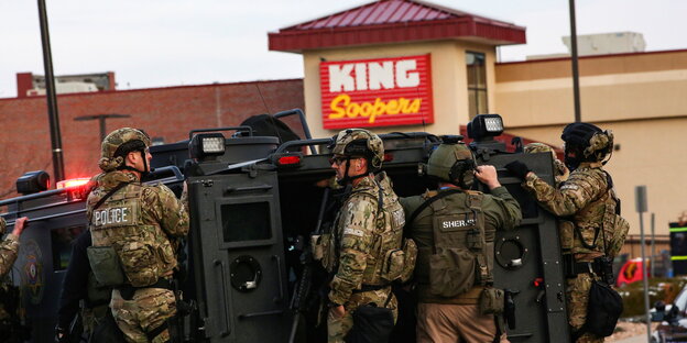 Schwerbewaffnete Poliziste mit ihrem gepanzerten Fahrzeug vor einem Einkaufszentrum