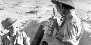 Zwei alliierte Soldaten machen im Schützengraben im Wüstensand eine Bombe einsatzbereit.