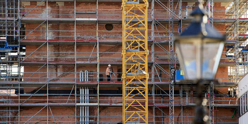 Vor dem roten Turm der Garnisonkirche in Potsdam stehen ein Baugerüst und ein gelber Kran.