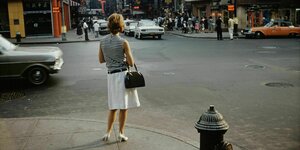 Frau in weißem Rock und gestreiftem Top steht an einer Straßenecke in New York