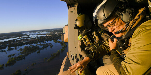 Premierminister Morrison fliegt in einem offenen Hubschrauber über überschwemmtes Land in Australien