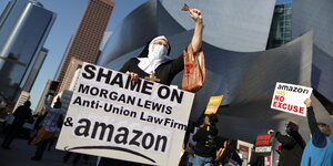 Ein Demonstrant als Nonne verkleidet mit einem Schild in der Hand auf dem steht "shame on you morgan Lewis Anti-Union Law Firm & amazon"