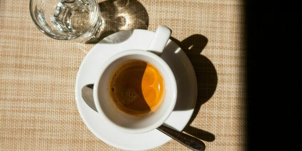 Eine Tasse Espresso und ein Glas Wasser von oben fotografiert