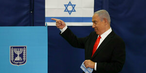 Ministerpräsident Benjamin Netanjahu bei der Stimmabgabe zeigt nach links und hat einen Stimmzettel in der hand