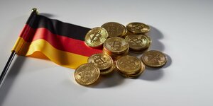 Bitcoin Münzen neben einer kleinen Deutschland-Flagge