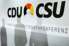 Schatten von drei Männern auf einer CDU/CSU-Werbewand