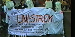 Studierende mit Kisten auf dem Kopf tragen ein Banner zum Studentenprotest 1988/89 mit der Aufschrift "Uni-Streik"