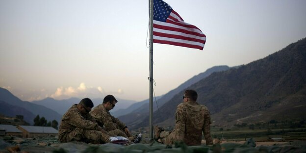 drei Soldaten und eine US-Flagge vor Bergen