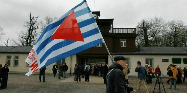 Ein Anhänger der Vereinigung VVN/BdA mit Fahne vor dem ehemaligen Konzentrationslager Buchenwald.